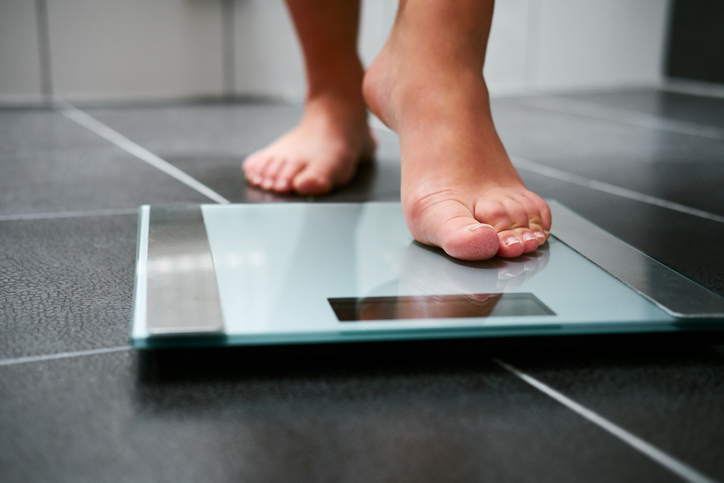 Woman stepping on scale, to monitor her weight during perimenopause